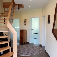 Eingangsbereich mit Glastüren zu Küche und Wohnzimmer sowie Standard-Treppe